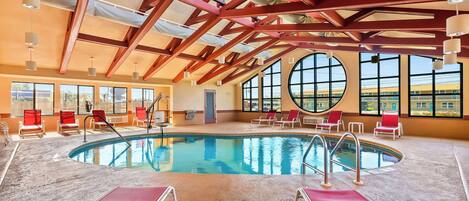 An indoor swimming pool with red chairs and a high ceiling with wooden beams.