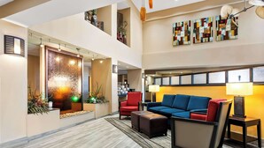 A spacious lobby with a modern design, featuring a blue sofa, red armchair, and a decorative wall with abstract art. - Comfort Suites (Panama City)
