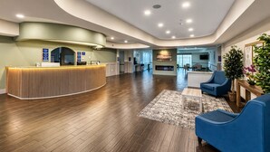 En modern hotellobby med en receptionsdisk, en sittgrupp och en öppen spis.
