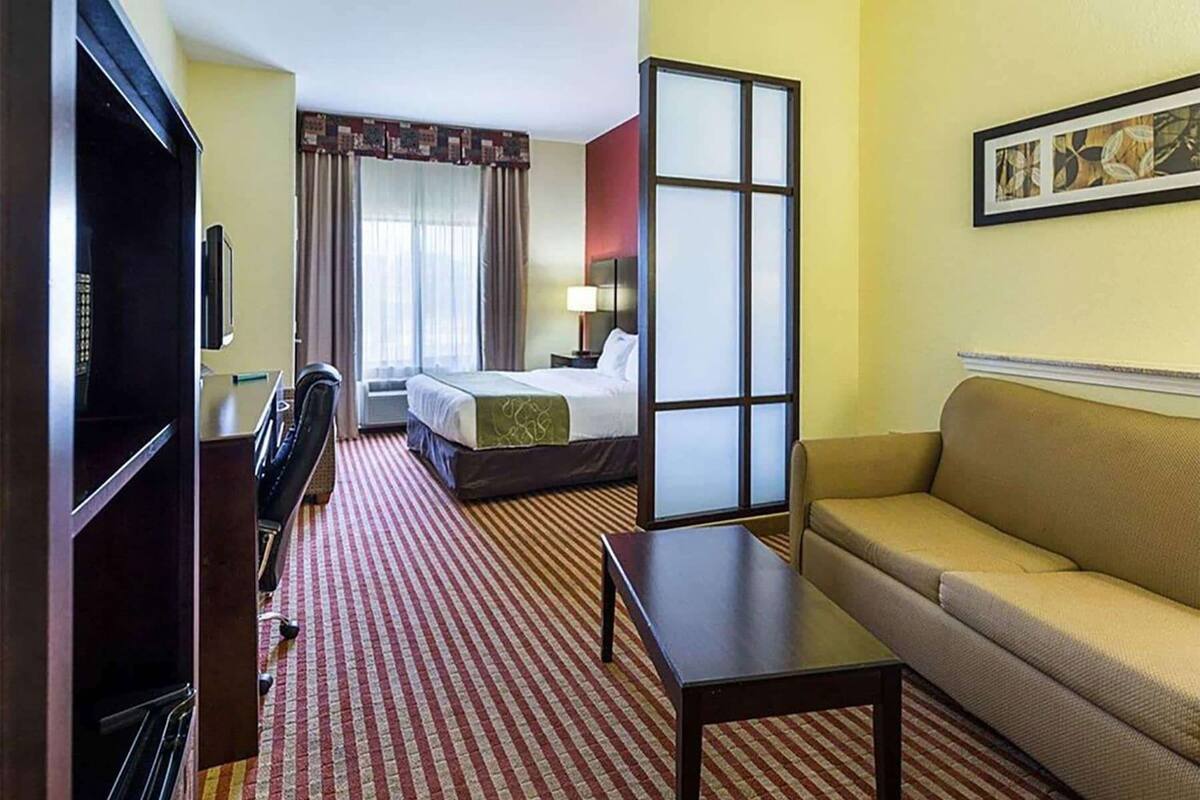 Una habitación de hotel con una cama, un sofá, un escritorio, una silla y una televisión.