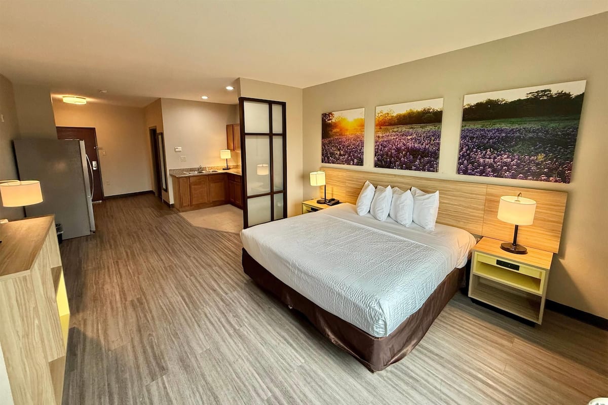 Habitación de hotel con una cama grande, un escritorio, una silla y vistas a un campo por la ventana.