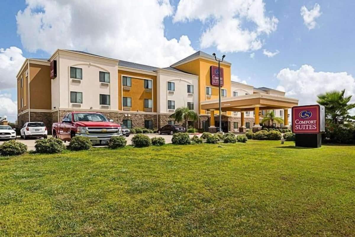 Un hotel con un patio central, varios espacios de estacionamiento y un letrero que indica que es un Comfort Suites.