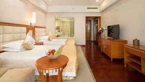 A hotel room with two beds, a TV, a desk, and a bathroom visible through a glass door. - Qinghe Jin Jiang International Hotel (Zhangjiajie)