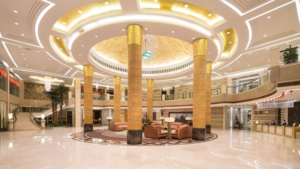 A spacious lobby with a central seating area, multiple floors, and a grand chandelier. - Qinghe Jin Jiang International Hotel (Zhangjiajie)