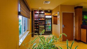 A hallway with a vending machine, a plant, and a door. - Fairfield Inn & Suites by Marriott Venice (Venice)