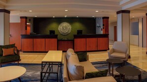 A lobby with a reception desk, seating area, and a decorative wall. - Fairfield Inn & Suites by Marriott Venice (Venice)