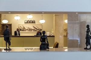 Una recepción con mostrador, tres estatuas y una pared con cuadros enmarcados.