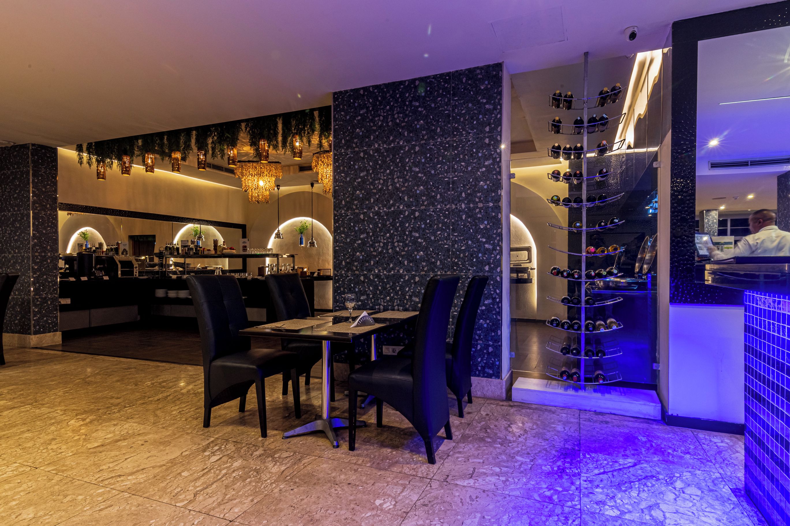 A restaurant with a bar area, seating, and a wine rack.