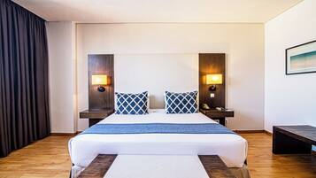 A hotel room with a bed, bedside tables, lamps, and a painting on the wall.