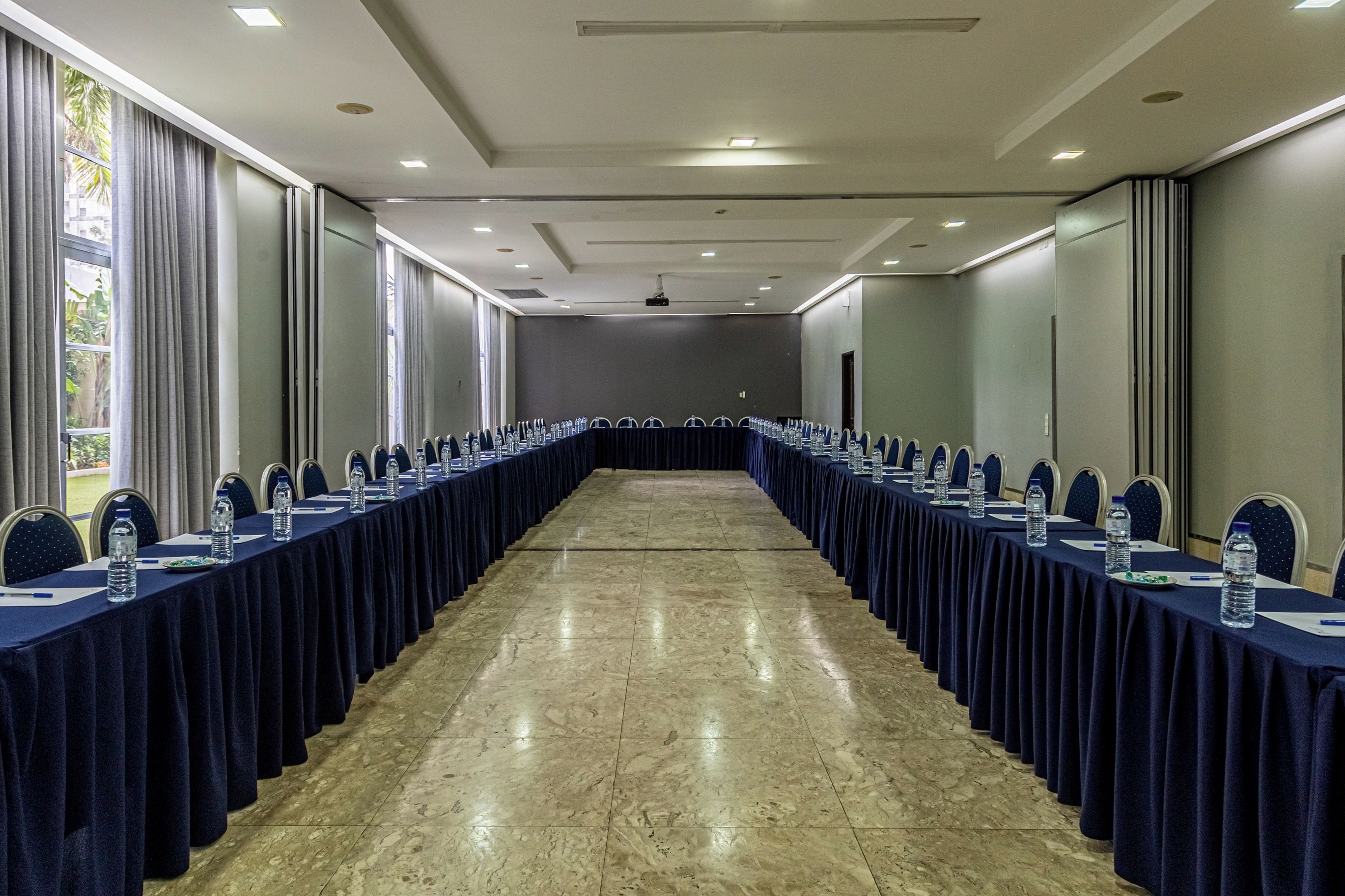 Une salle de conférence avec une longue table, des chaises et des bouteilles d’eau.