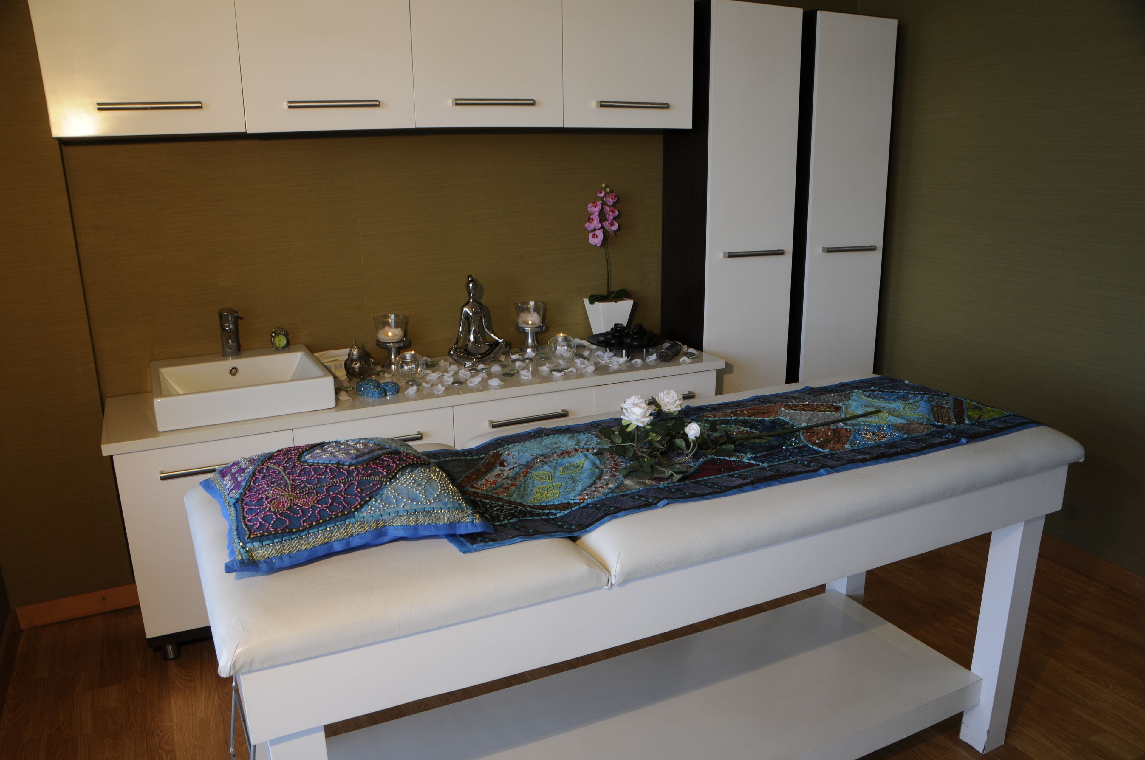 Una habitación con un banco blanco, un lavabo y un mueble con cajones.