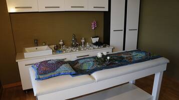 Una habitación con un banco blanco, un lavabo y un mueble con cajones.