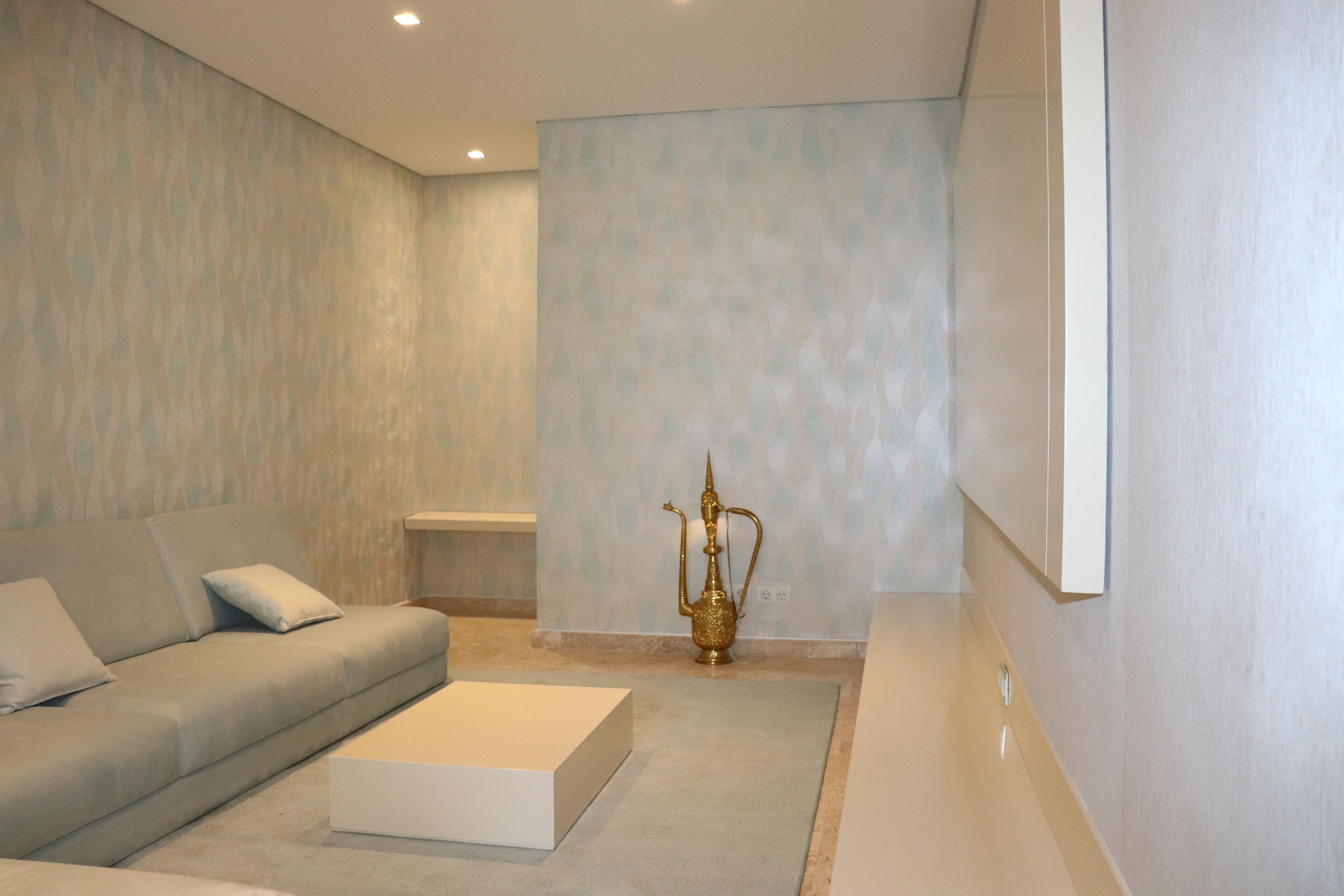 A modern living room with a grey sofa, a white coffee table, and a decorative golden vase.
