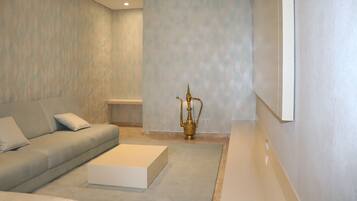 A modern living room with a grey sofa, a white coffee table, and a decorative golden vase.