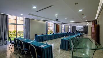 A conference room with long tables, chairs, and a projector.
