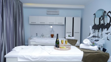 Una habitación de hotel con una cama, una camilla de masaje, un minibar y un espejo grande.