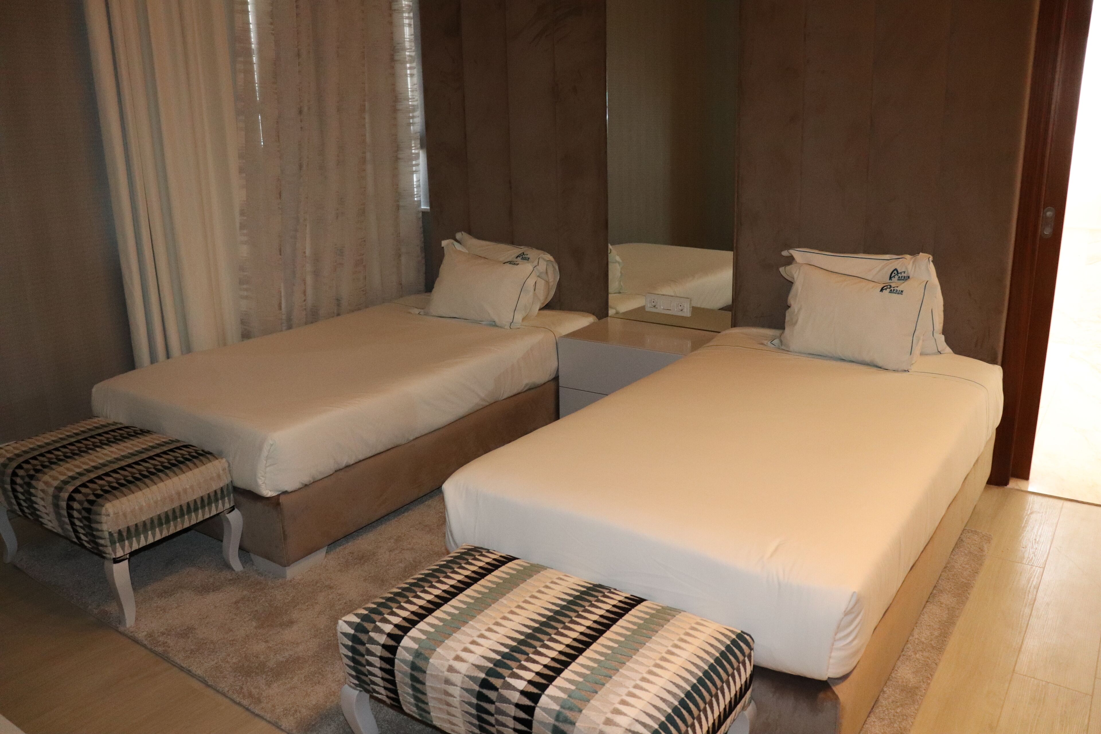 Una habitación de hotel con dos camas individuales, una mesita y un banco.
