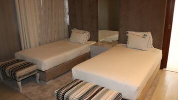 Una habitación de hotel con dos camas individuales, una mesita y un banco.