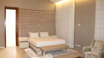 A bedroom with a large bed, a bedside table, a bench, a chair, and a wooden coffee table.
