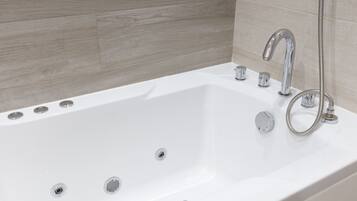 A modern bathroom with a white bathtub, chrome fixtures, and a wooden wall panel.