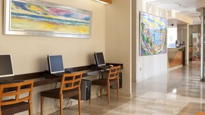 A reception area with a long counter, multiple computer stations, and two large paintings on the walls. - Hotel Olympia Ronda II (Puig)