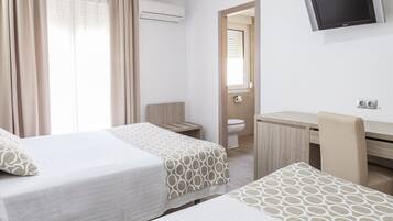 Une chambre d’hôtel avec deux lits, un bureau, une chaise, une télévision et une salle de bain.