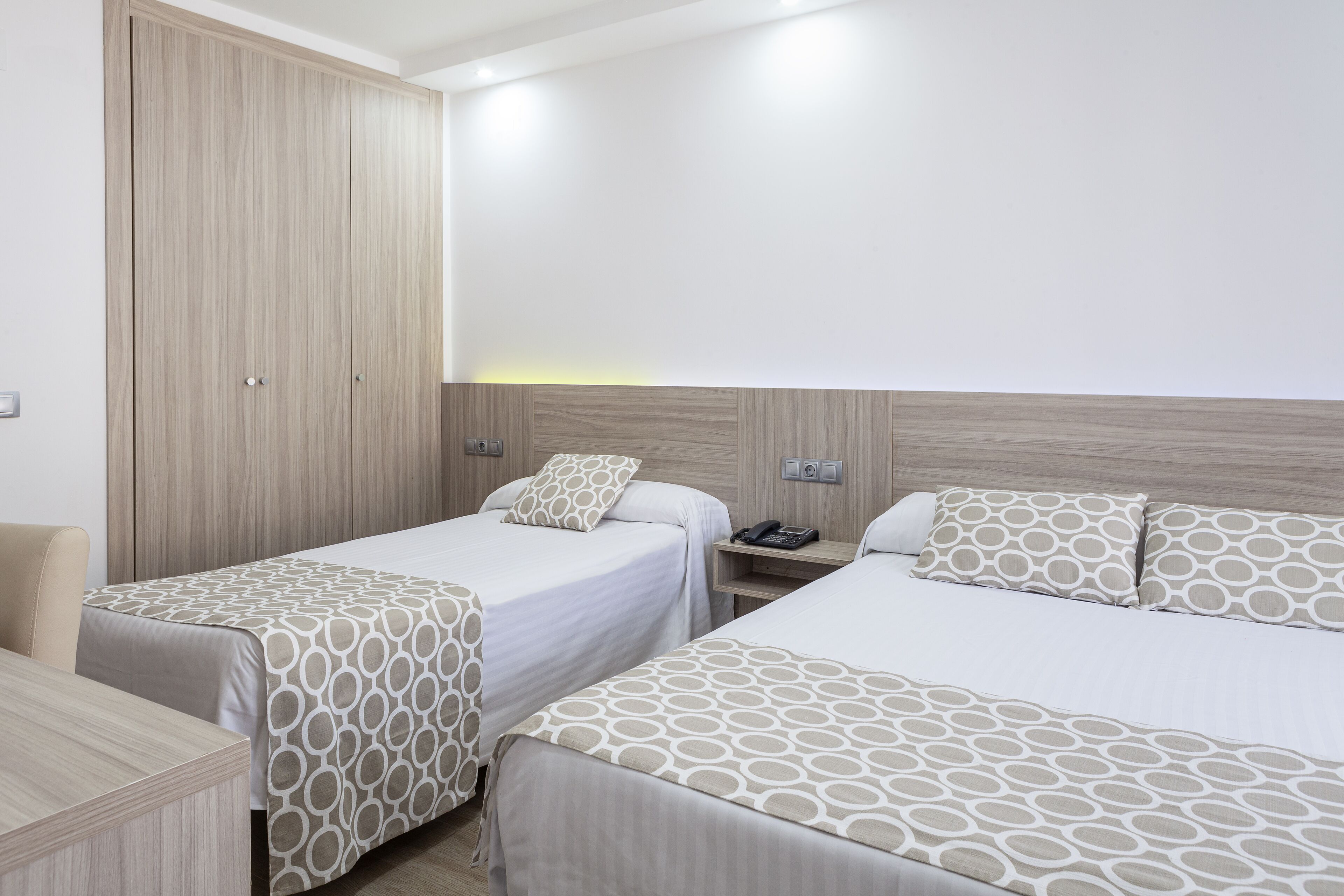 Habitación de hotel con dos camas, un escritorio y un armario.
