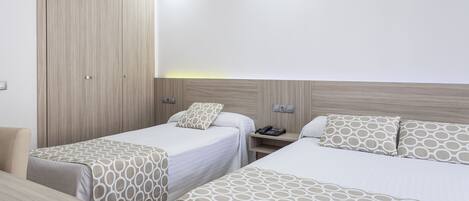 Habitación de hotel con dos camas, un escritorio y un armario.