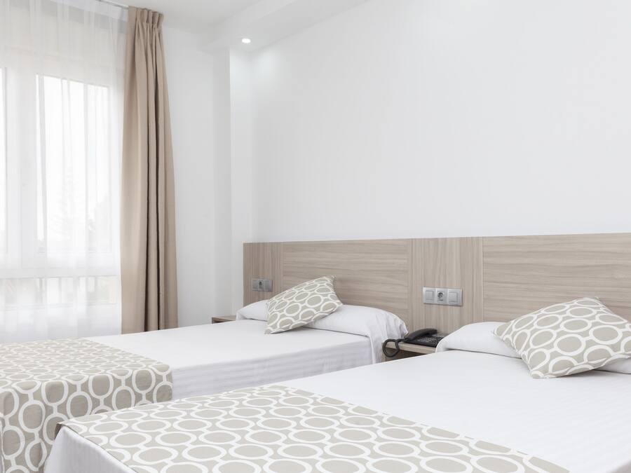 Une chambre d’hôtel avec deux lits, chacun recouvert d’une couvre-lit à motifs et agrémenté d’oreillers assortis.
