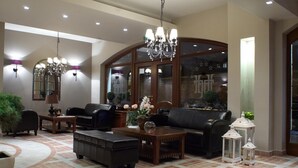 A spacious living area with a large arched window, leather sofas, a wooden coffee table, and decorative items.
