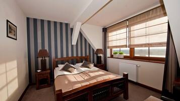 Quarto com cama de madeira, papel de parede listrado, janela com vista e radiador.
