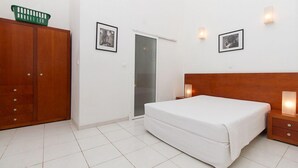 Un dormitorio con cama, armario de madera y dos luces fijadas a la pared.