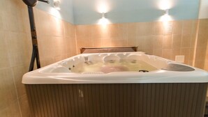 Un jacuzzi en un baño con azulejos color crema y suelo de madera.