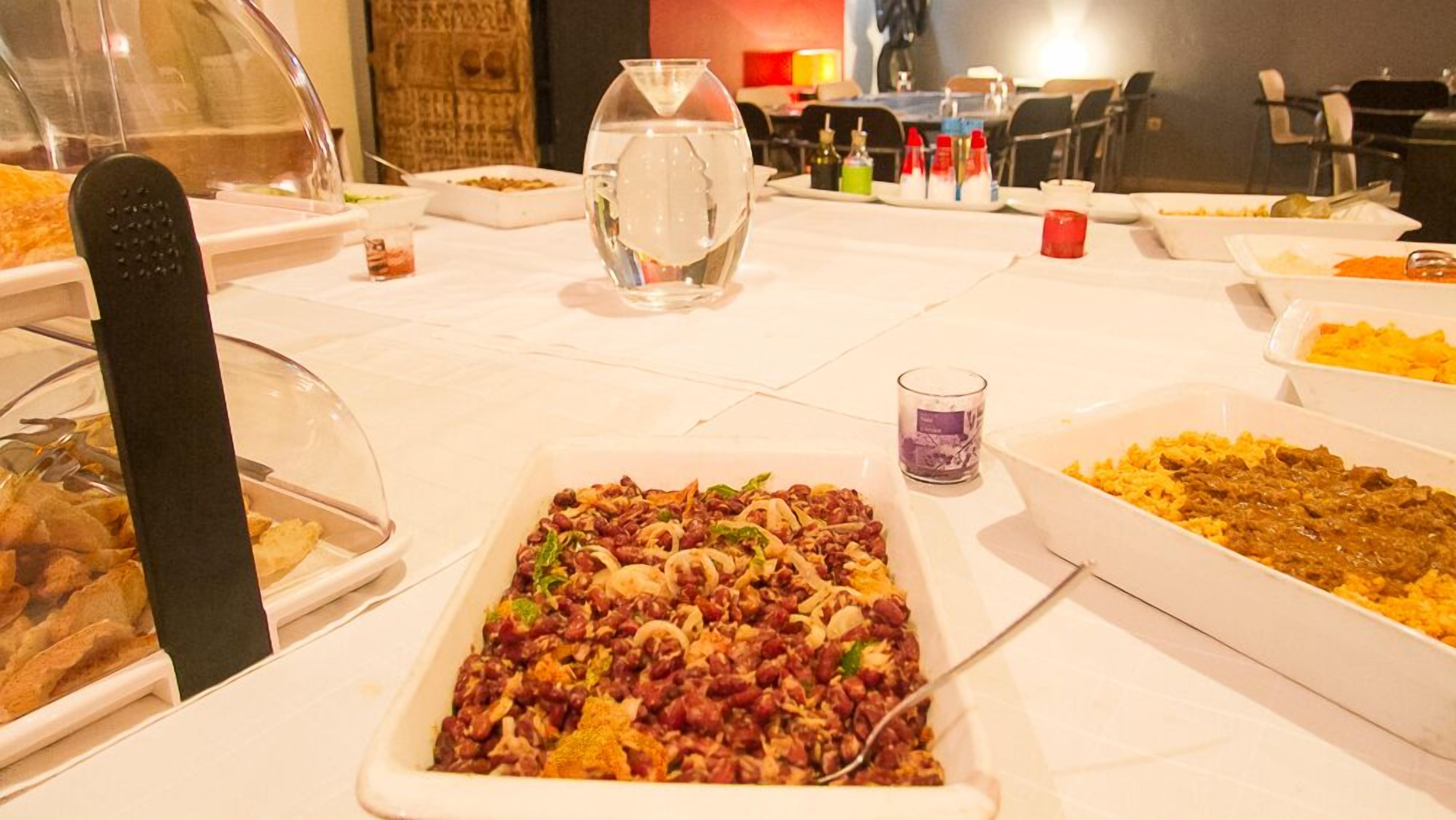 Una mesa de buffet con diversos platos, incluyendo una ensalada de frijoles, arroz y otros alimentos preparados.