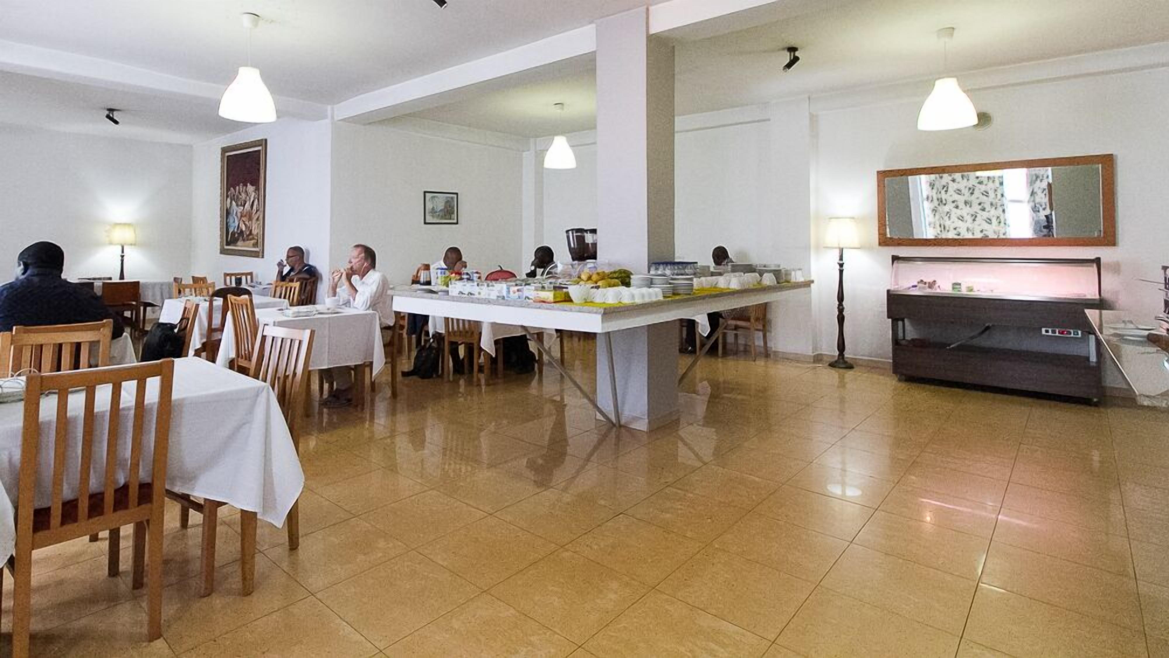 A dining area with tables and chairs, a buffet counter, and a large mirror on the wall.