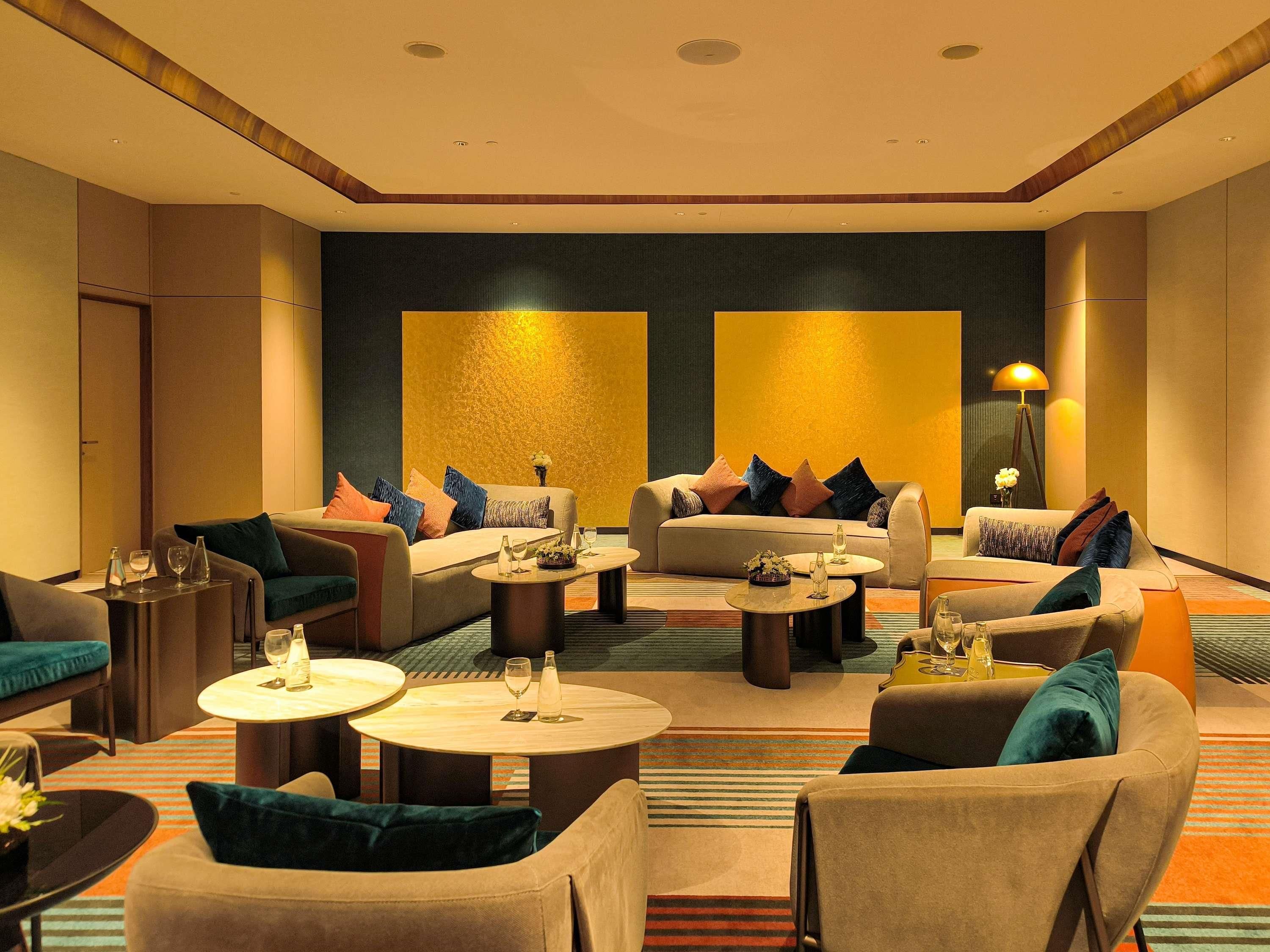 Un vestíbulo de hotel con varias zonas de estar, incluyendo sofás y sillones, dispuestos alrededor de una mesa de centro.