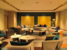 Un vestíbulo de hotel con varias zonas de estar, incluyendo sofás y sillones, dispuestos alrededor de una mesa de centro.