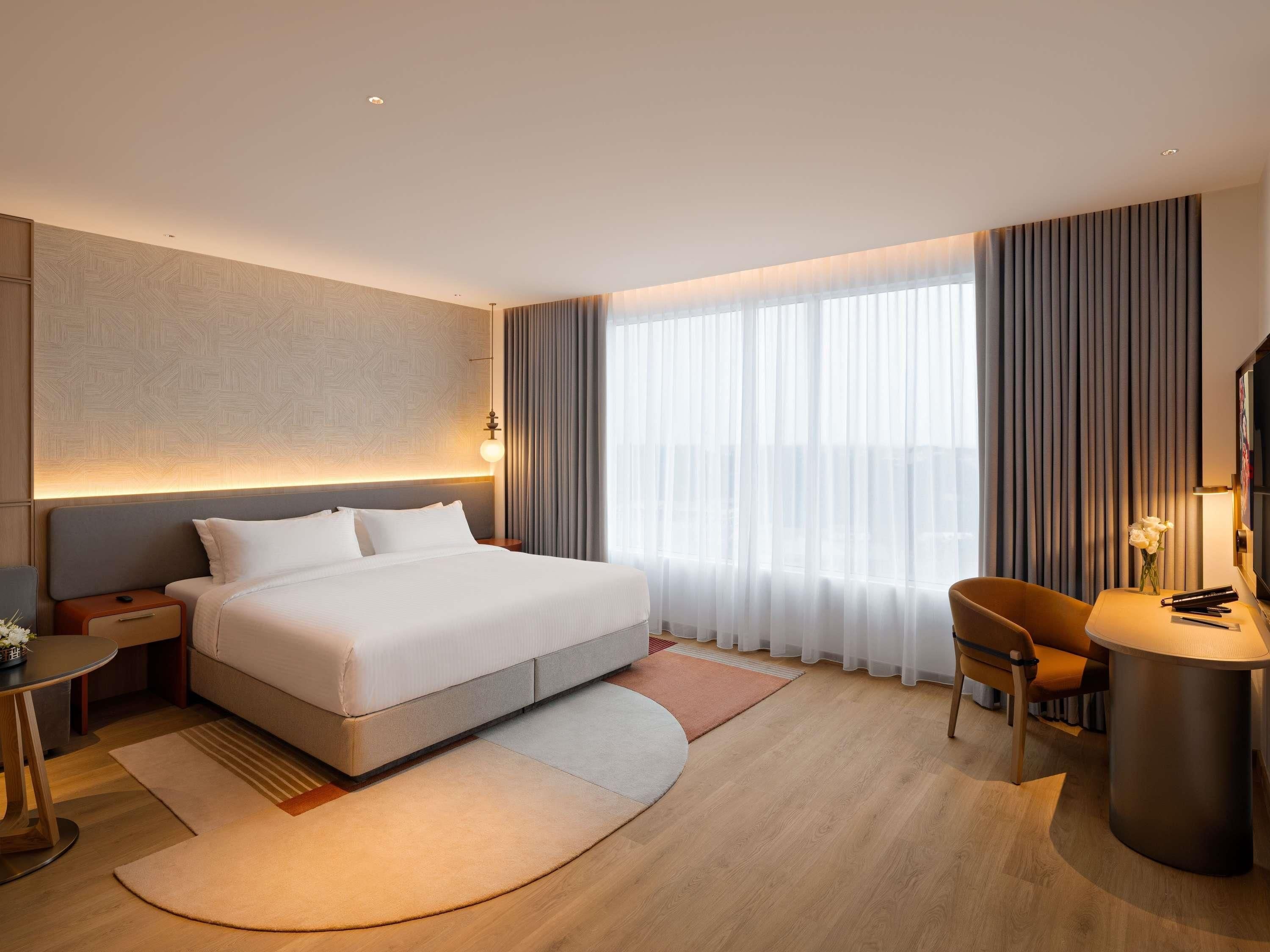 Una habitación de hotel moderna con una cama grande, un escritorio, una silla y un televisor.