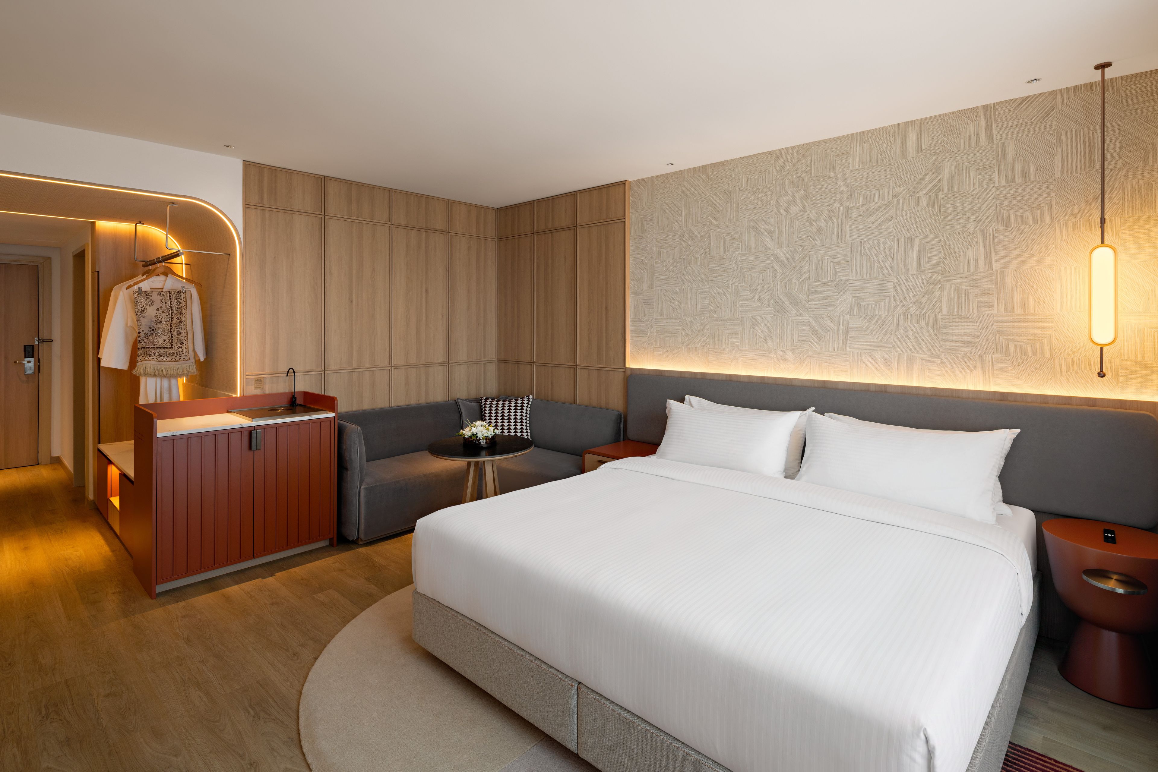 Moderni hotellihuone, jossa on suuri sänky, oleskelualue, työpöytä ja vaatekaappi.