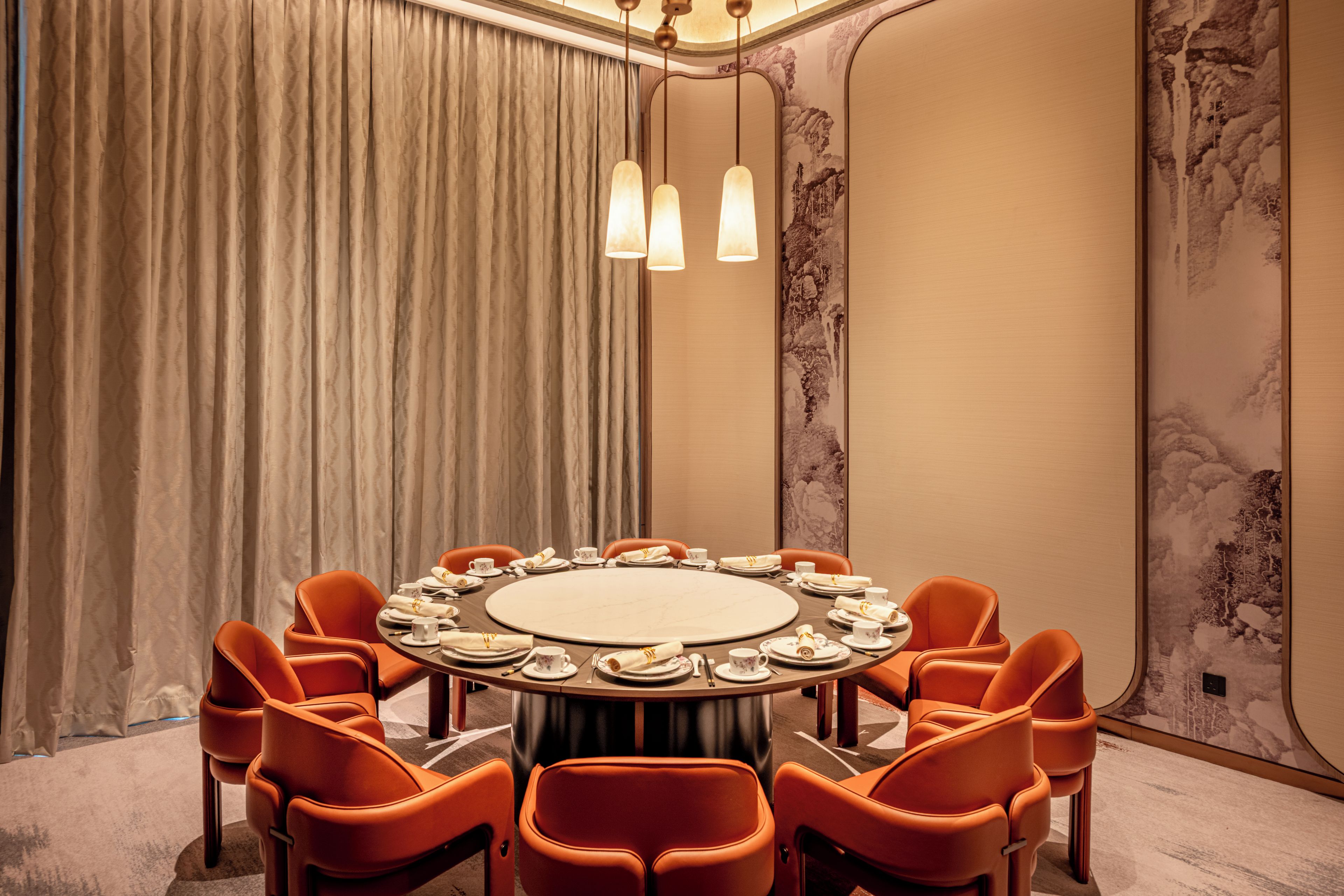 A conference room with a round table, orange chairs, and a curtain backdrop.