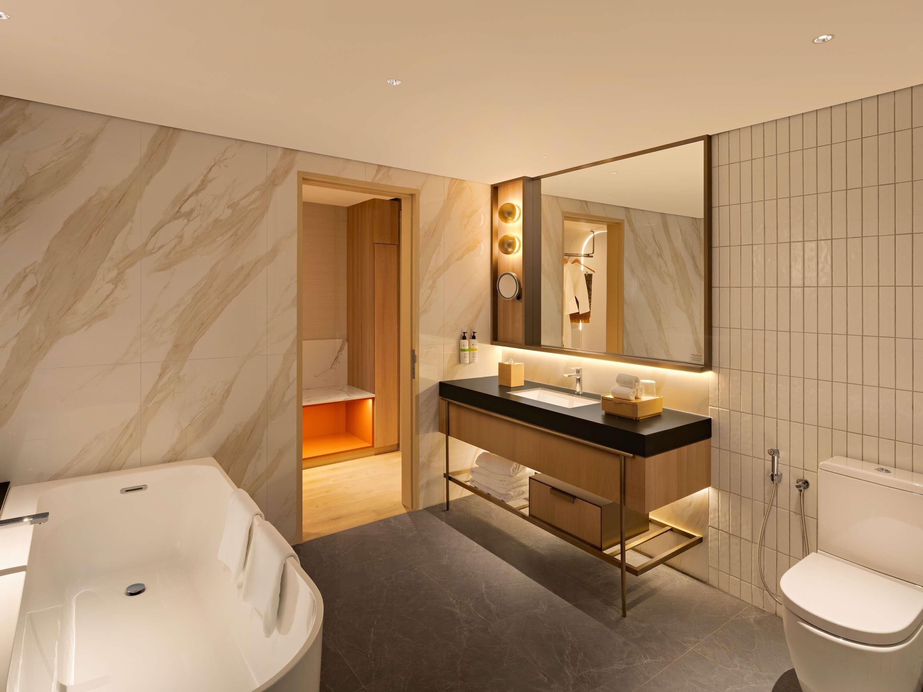 Un baño moderno con una bañera independiente, un tocador con espejo y un inodoro.