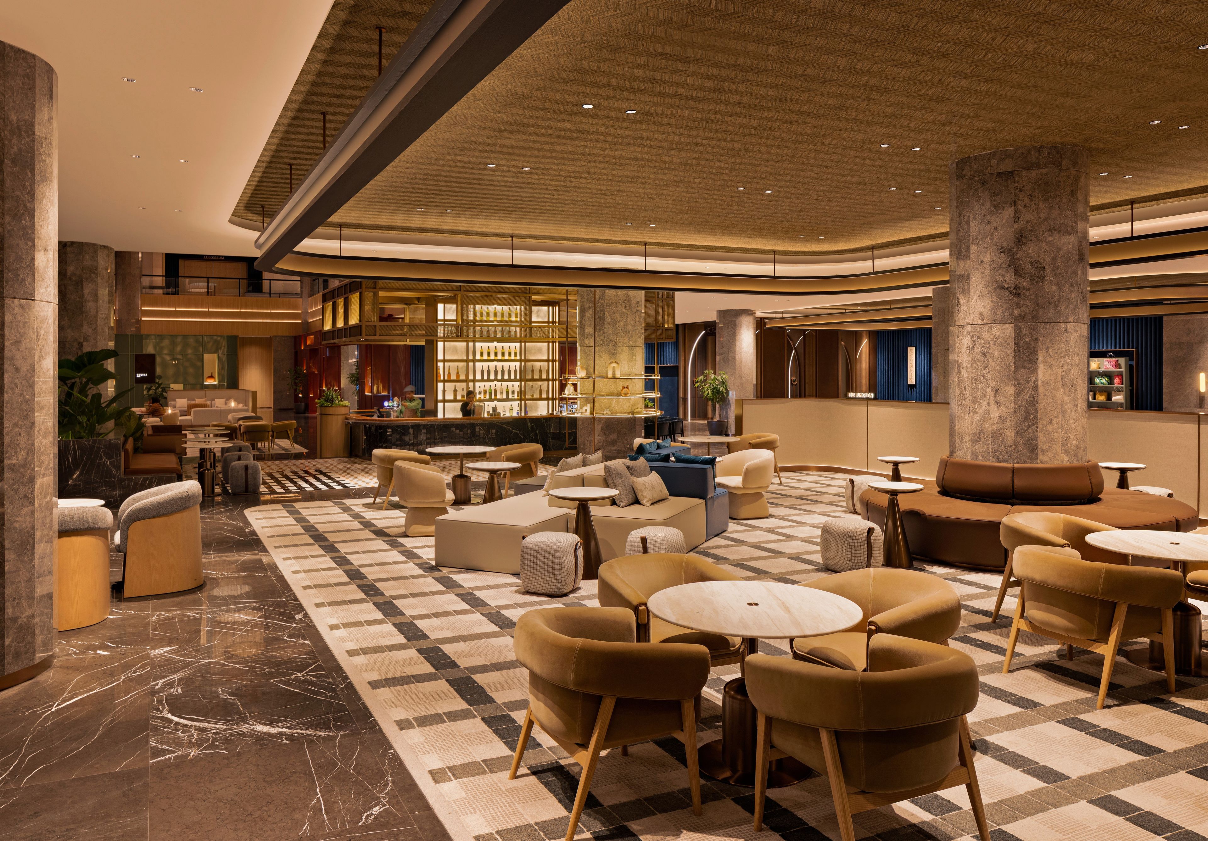 A spacious lobby with a checkered floor, seating areas, a bar, and a reception desk.