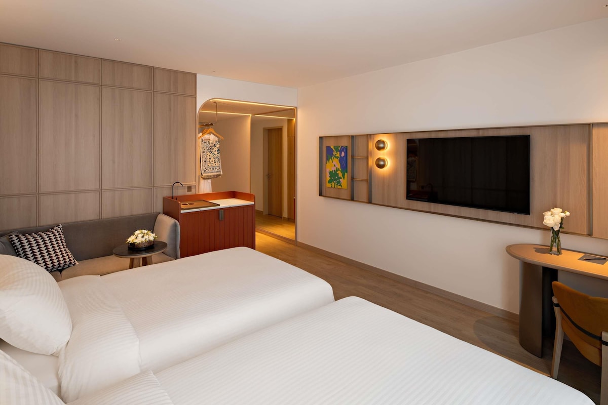 Una habitación de hotel con cama, escritorio, televisor y zona de estar.
