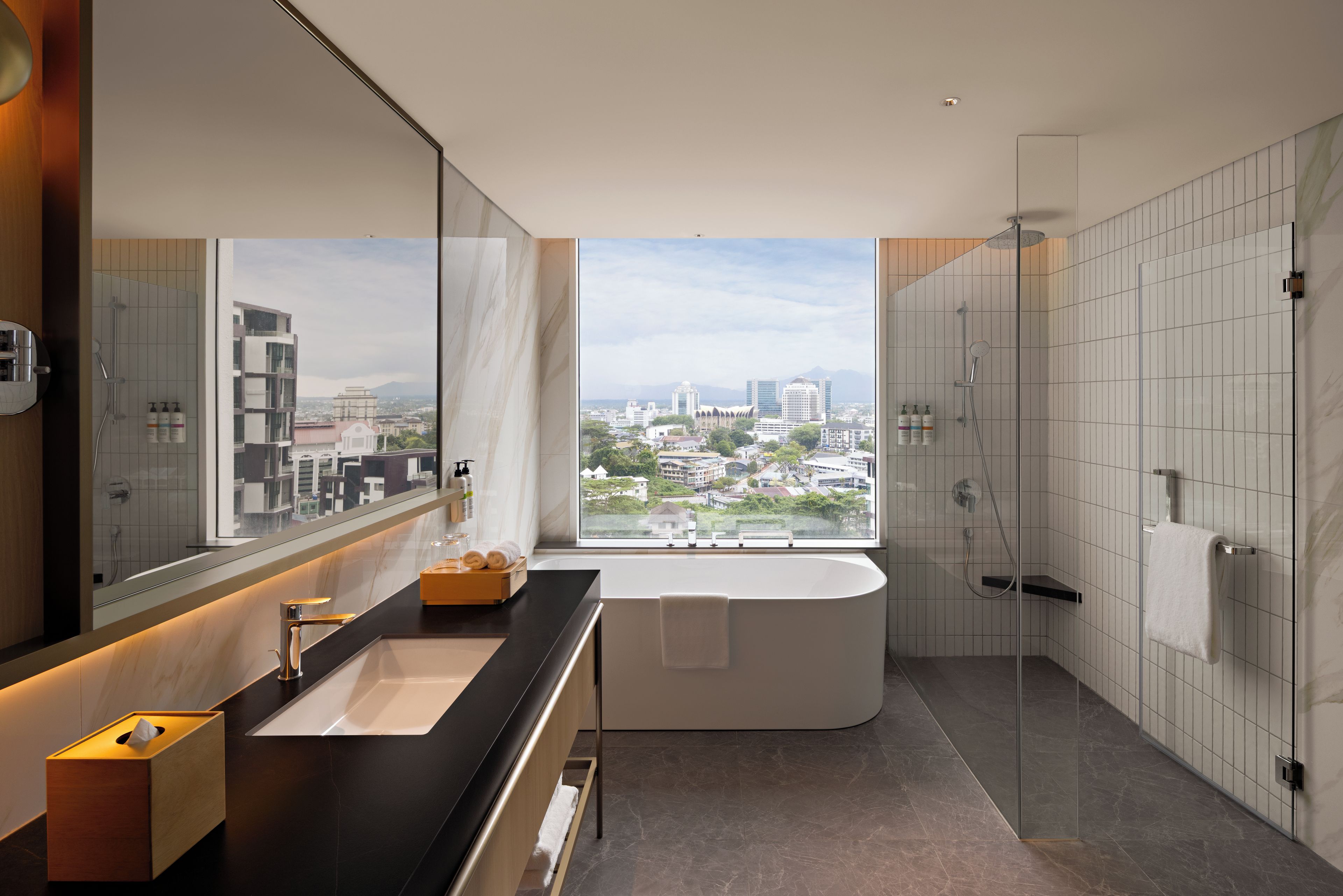 Ein modernes Badezimmer mit großem Fenster, einer Badewanne, einer Dusche und einem Waschtisch.