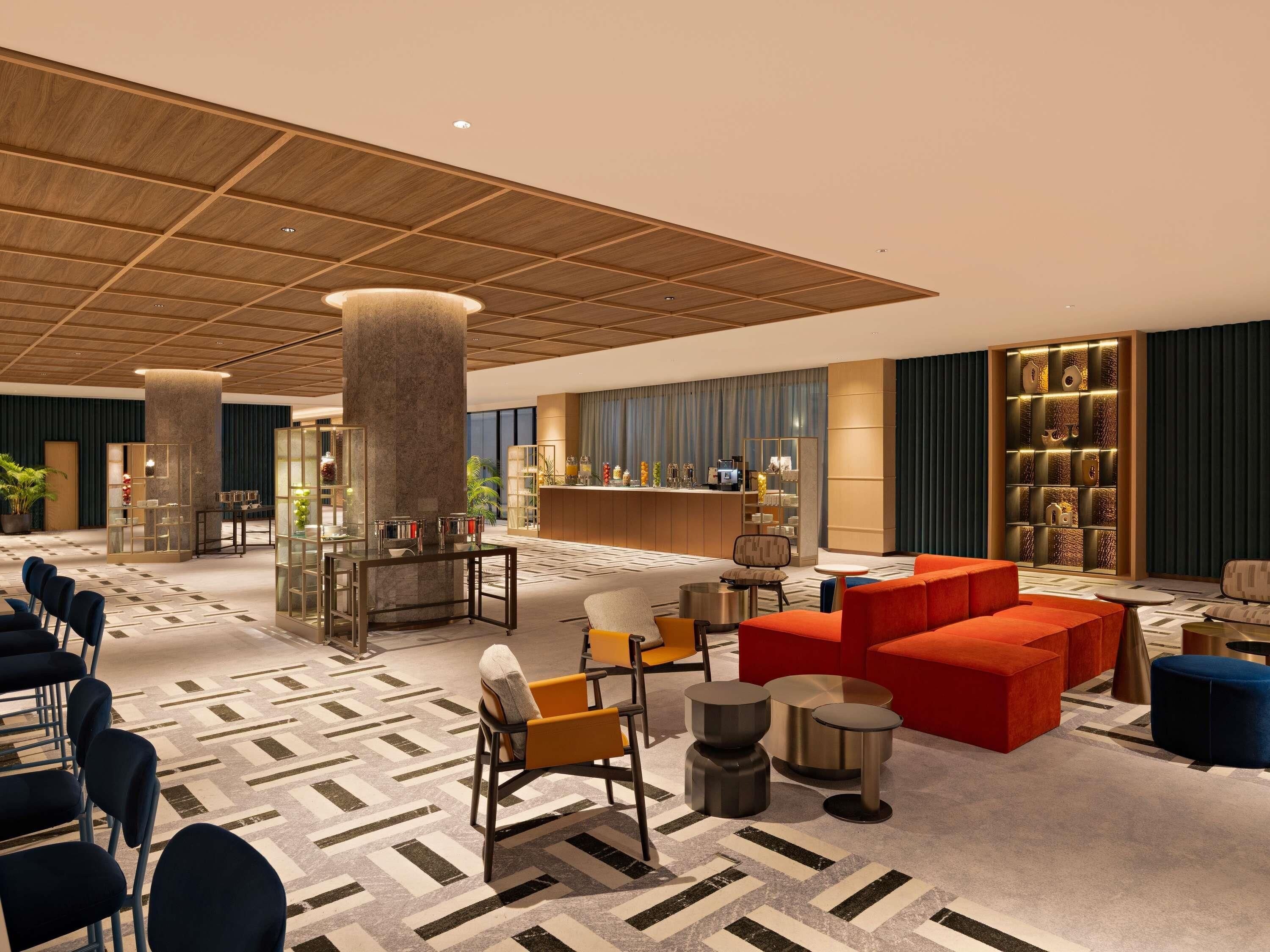 Een hotel lobby met een receptiebalie, een zithoek en een bar.