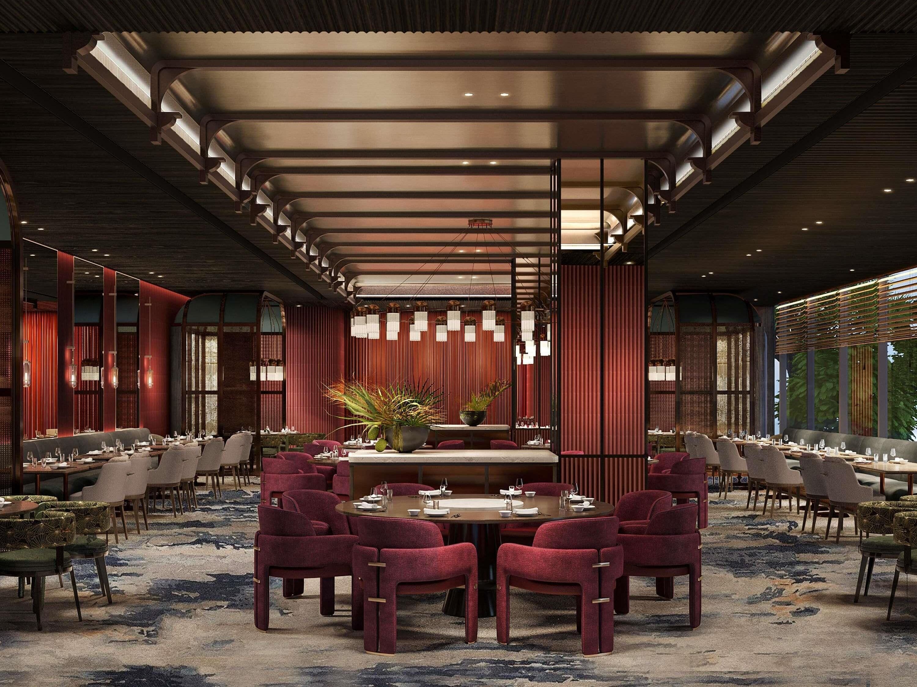 A spacious dining area with a long table, red upholstered chairs, and a decorative centerpiece.
