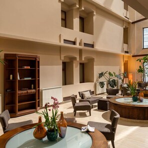 A spacious indoor area with a high ceiling, a central seating area with sofas and a coffee table, and a large wooden bookshelf. - Pietroasa Hotel, Buzau (Buzau)
