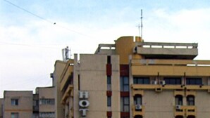 Egy többemeletes szállodával, melynek homlokzatán feltűnően nagy betűkkel szerepel a „HOTEL PIERROSA” felirat.