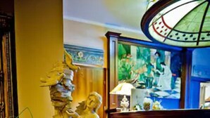 A lobby with a decorative fountain, a patterned floor, and a reception desk with a lamp. - Hotel Gaja (Poznan)