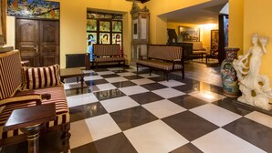 A lobby with checkered flooring, wooden benches, and a large window with stained glass. - Hotel Gaja (Poznan)